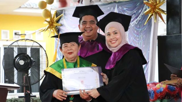 Bupati Bintan Roby Kurniawan bersama Ketua TP PKK Bintan Hafizha Rahmadhani menyerahkan piagam kelulusan kepada peserta Sekolah Lansia Kasih Ibu Desa Sebong Lagoi dalam prosesi wisuda lansia Tahun Pelajaran 2025.