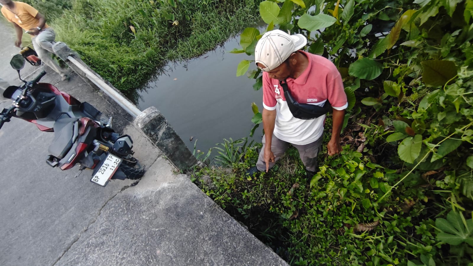 Ketua Pemuda RW 009, M Sadi, saat menunjukkan kondisi jembatan penghubung di wilayah itu yang sudah mulai amblas, Senin (10/8/2026) (f-pijarkepri.com)