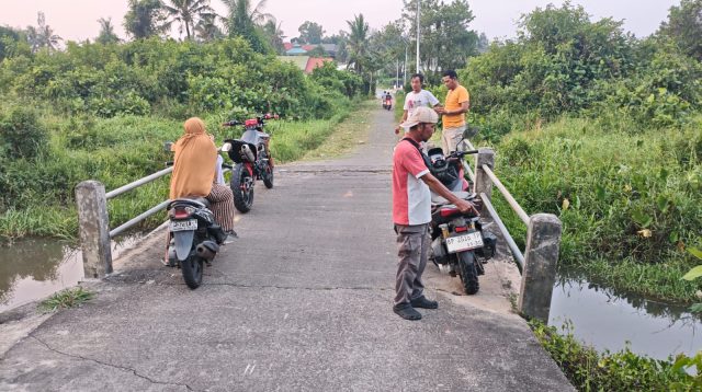 Ketua Pemuda RW 009, M Sadi, saat menunjukkan kondisi jembatan penghubung di wilayah itu yang sudah mulai amblas, Senin (10/8/2026) (f-pijarkepri.com)